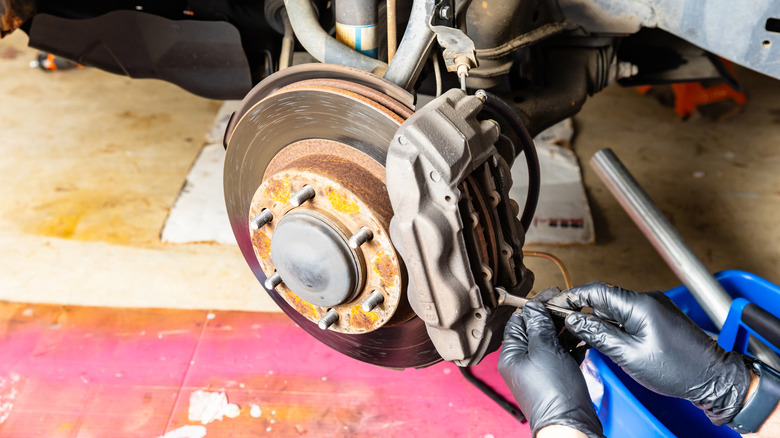 Mechanic working on replacing brake pads on vehicle.