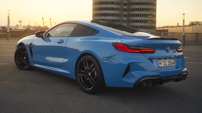 Rear 3/4 shot of a parked BMW M8 Coupe with a building in the background