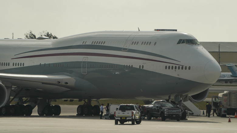Boeing 747 sitting at the airport with vehicles around it.