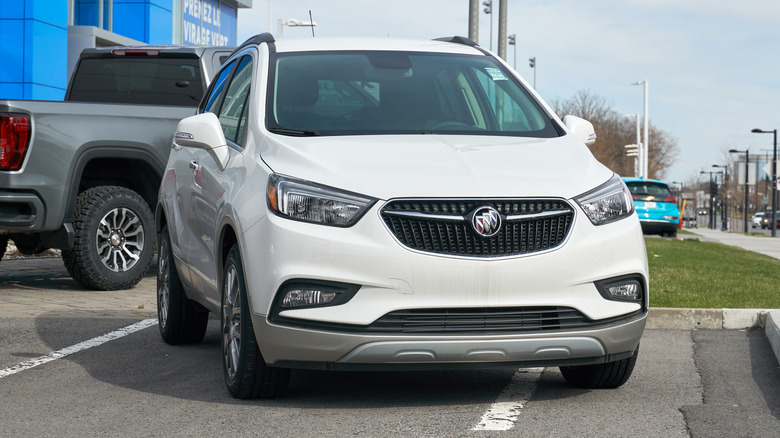A two-tone white and silver Buick Encore outside a dealership, front 3/4 view