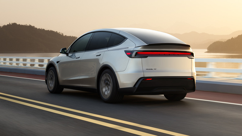 Tesla Model Y L driving along coastal road, rear-left 3/4 view
