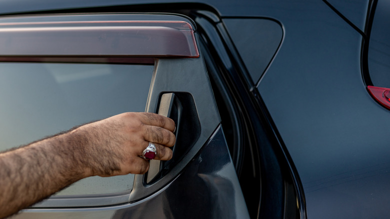 Rear door handle of Nissan Juke close-up with a person actuating the latch