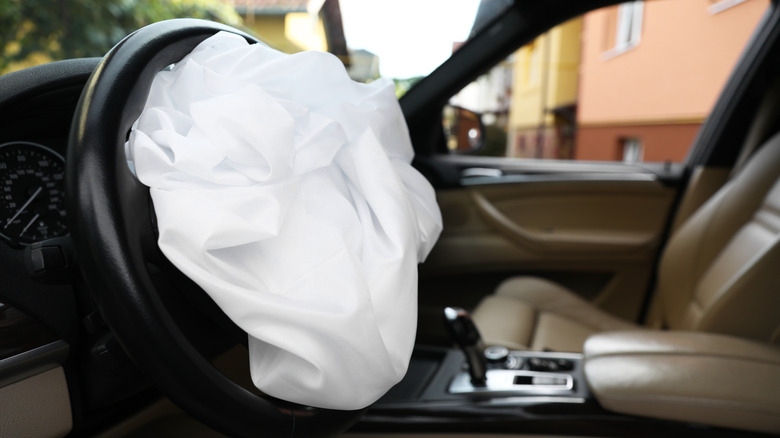 A deployed airbag inside what appears to be a BMW with cream leather seats
