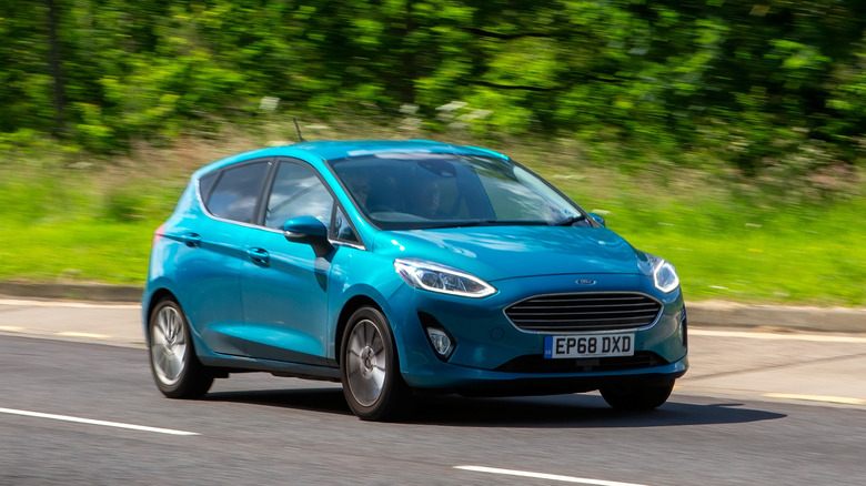 A blue Ford Fiesta on the move, front 3/4 view, UK plates