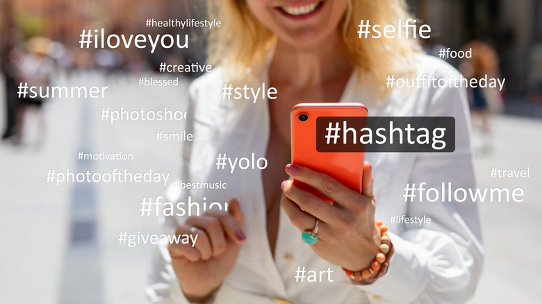 woman holding a smartphone, different hashtags on screen