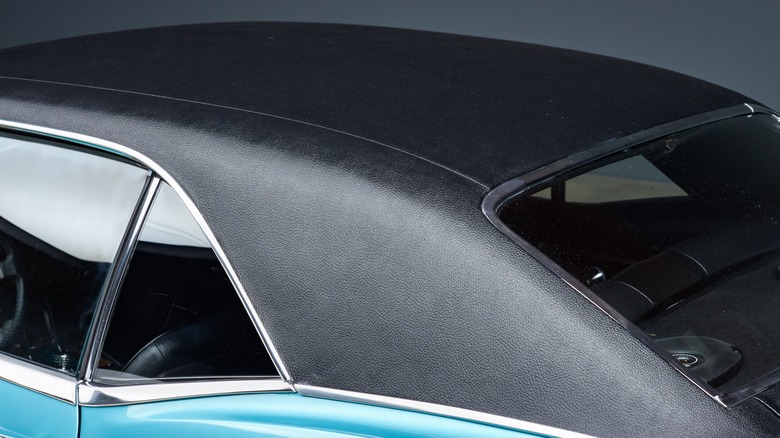 A close-up of a black vinyl top on a teal colored classic car