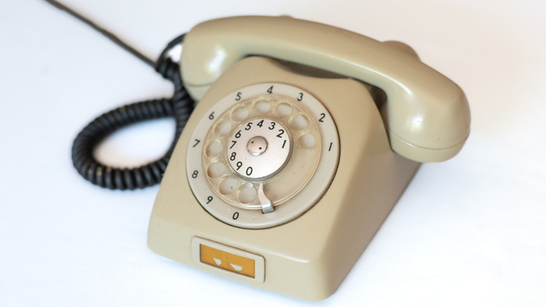A tan rotary phone on a white table