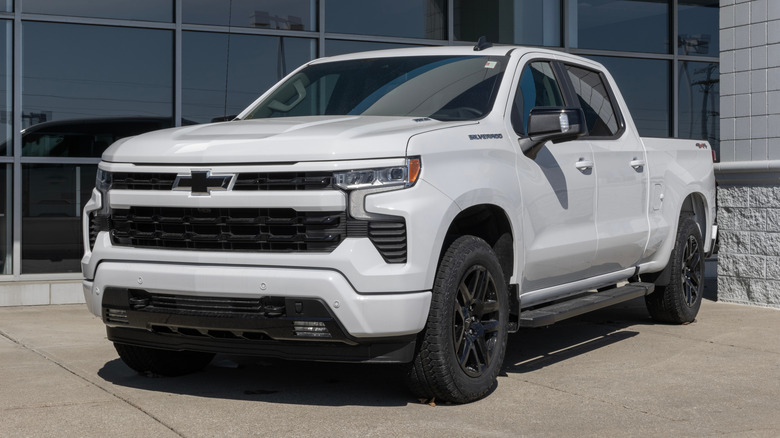 A 2025 Chevrolet Silverado 1500 in white outside a dealership, front 3/4 view