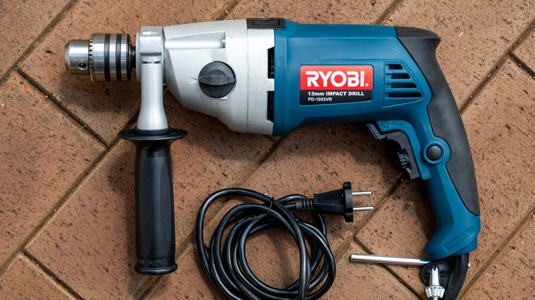 A blue Ryobi corded drill on stone.