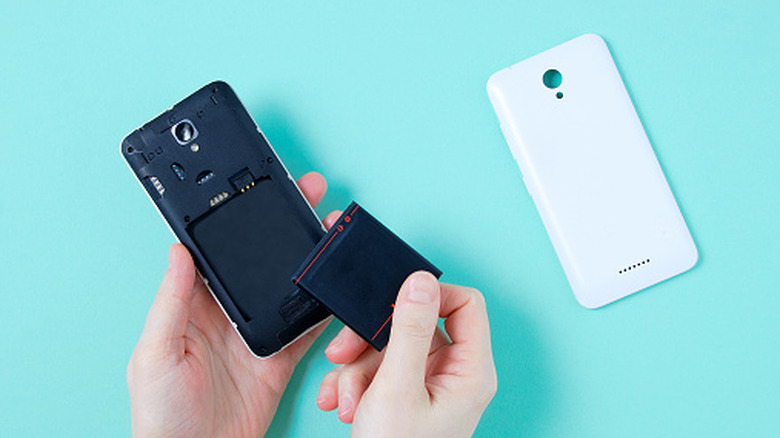 A person's hands removing a battery from a phone