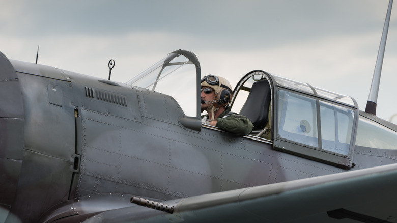 Fighter pilot at Duxford Flying Legends Airshow sitting in cockpit with canopy open.