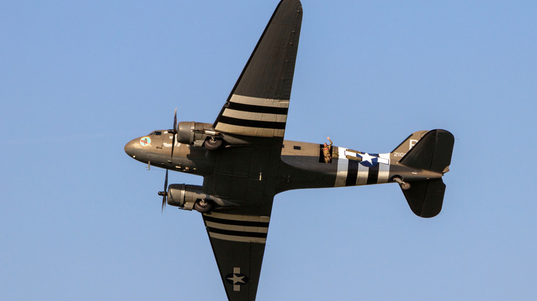 A World War II- era Douglas C-47A Skytrain Dakota transport plane sporting invasion stripes flies over Kleine Brogel airbase.