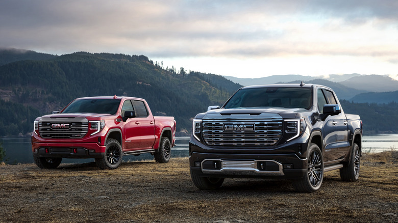 Two 2022 GMC Sierra 1500 pickup trucks parked side-by-side off-road, front-left view