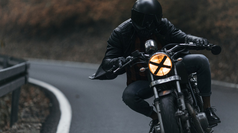 A biker riding the bike on highway with X on headlight