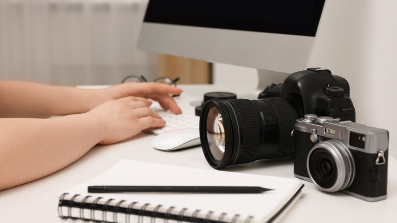 two cameras sitting on a desk next to a computer