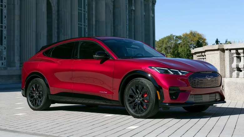 A 2025 Ford Mustang Mach-E in red with classic architecture in the background