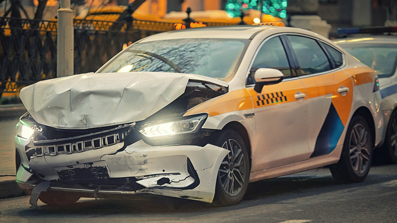 Front view of taxi on street showing front crumple zone after accident