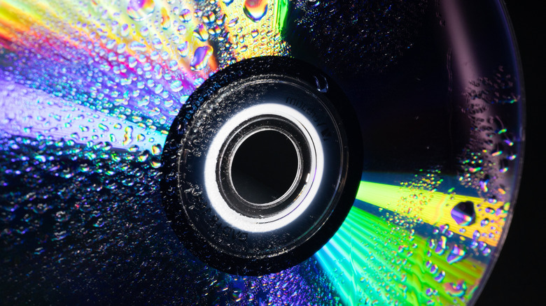 Close up of CD covered with water droplets and rainbow light reflection