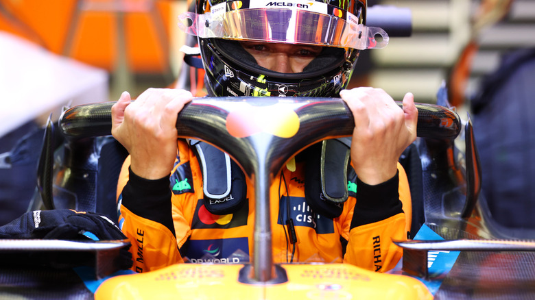 Lando Norris climbing into McLaren race car for testing