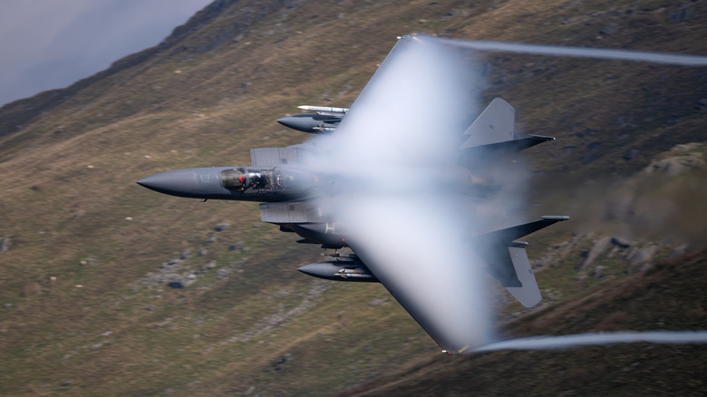 An F-15E Strike Eagle low flying over hills