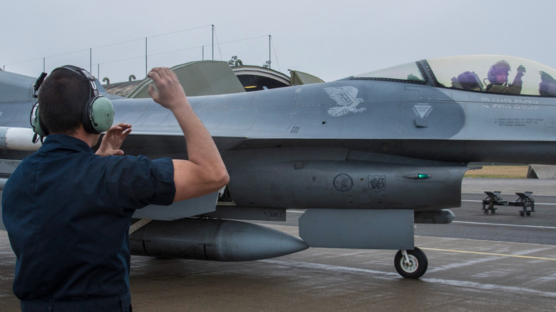 Claw motion performed between ground staff and Air Force pilot.