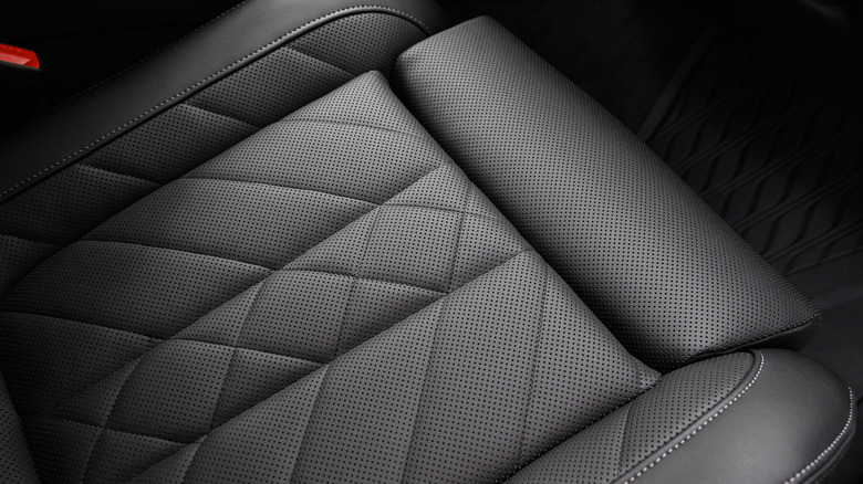 Close-up shot of a black perforated leather seat surface with stitching details