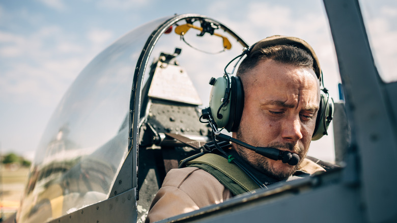 A pilot wearing a headset conducts the pre-flight checks in the cockpit of an Supermarine Spitfire vintage aircraft before a flight.