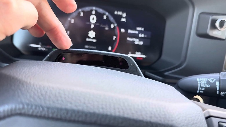 A man pointing to a camera mounted in the steering wheel that faces the driver