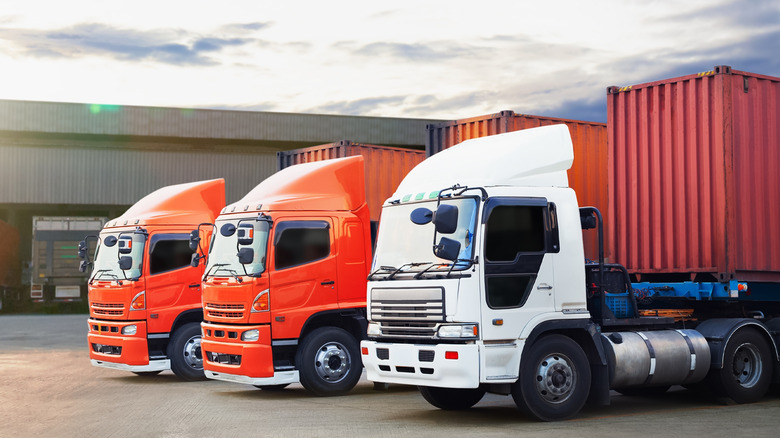 Three cabover semi trucks parked in a row