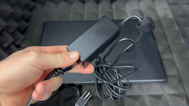 Close up of hand holding laptop charger brick