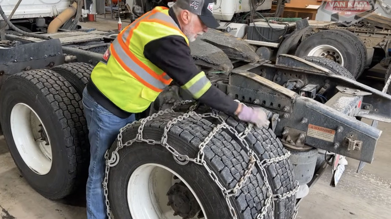 A trucker demonstrates how to install chains on a semi
