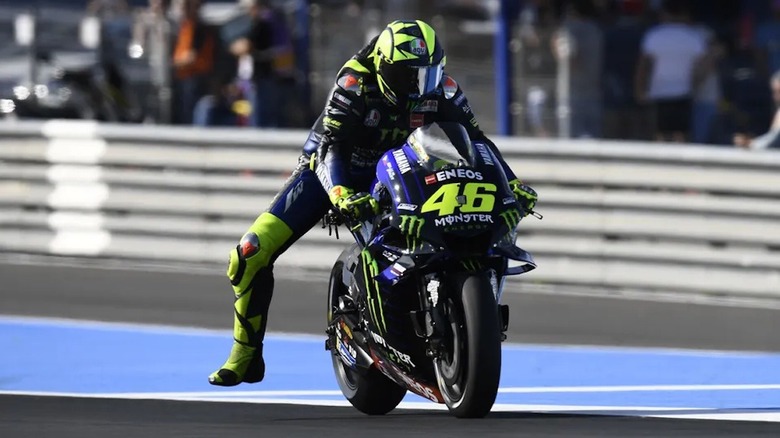 Valentino Rossi dangling a leg off his racing sport bike on the racetrack