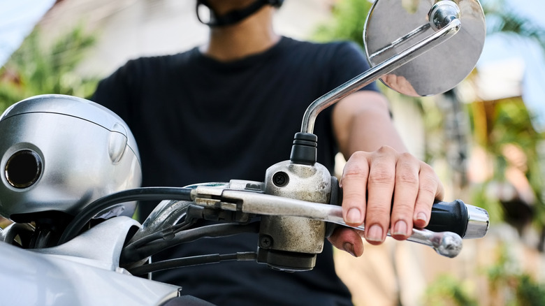 Person sitting on a motorycle with bar end weights installed on the handlebar