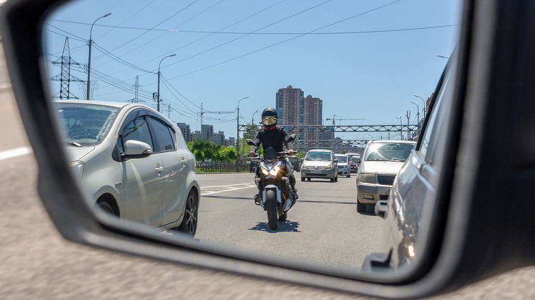 Motorcycle on the road being viewed through a car's side mirror.