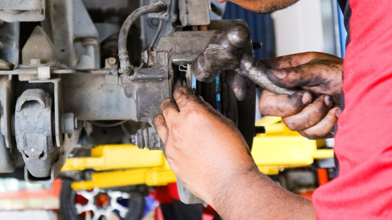 A person repairing a car's brake elements.