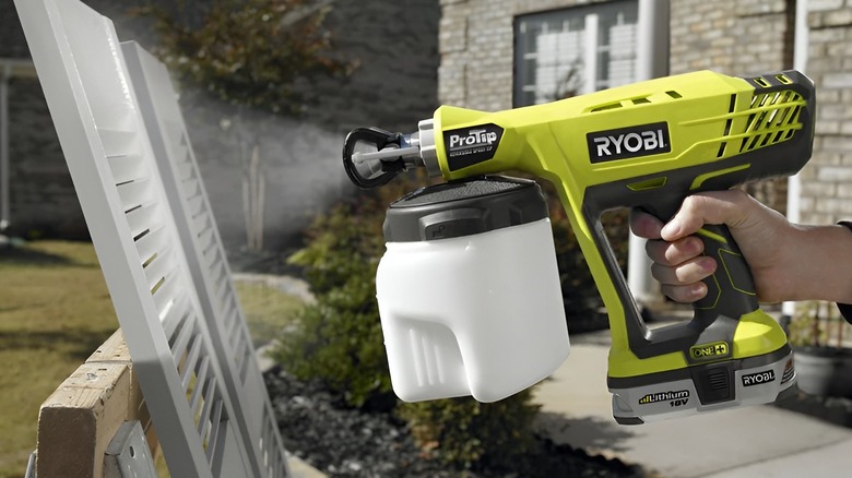 Person spraying wood surface with Ryobi paint sprayer