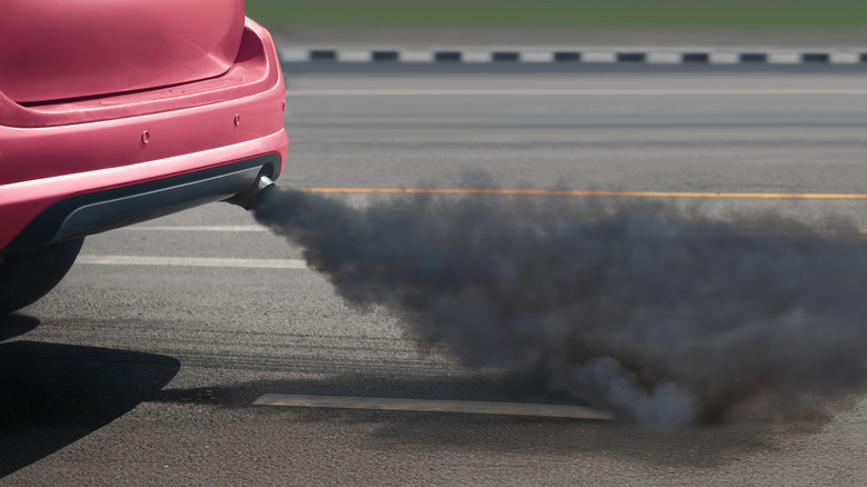 A red car releasing a lot of black smoke through the exhaust