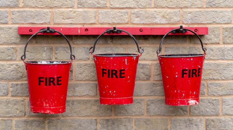 Red Buckets Hanging On A Wall With "Fire" Written On Them