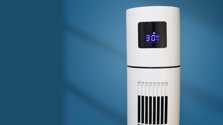 A portable air conditioner showing 30 degrees Celsius in front of a blue wall.