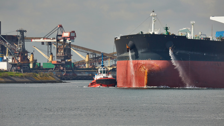 Tug boat assisting cargo ship in port
