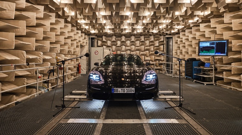 Black Porsche Taycan in an acoustic test chamber surrounded by microphones