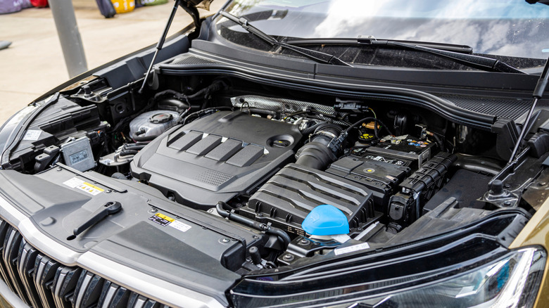 A close-up of a car's engine bay covered with plastic covers