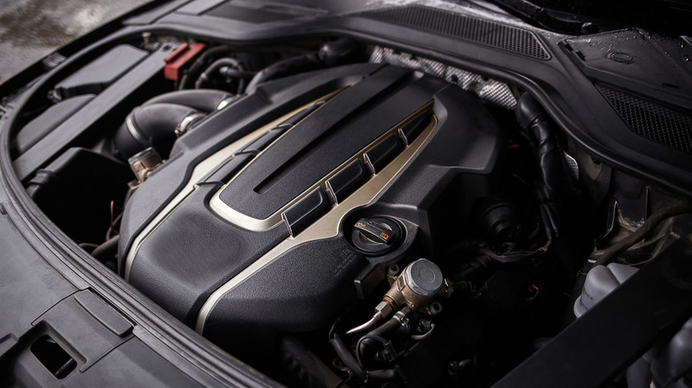 Close-up of a car's engine bay with a large plastic engine cover