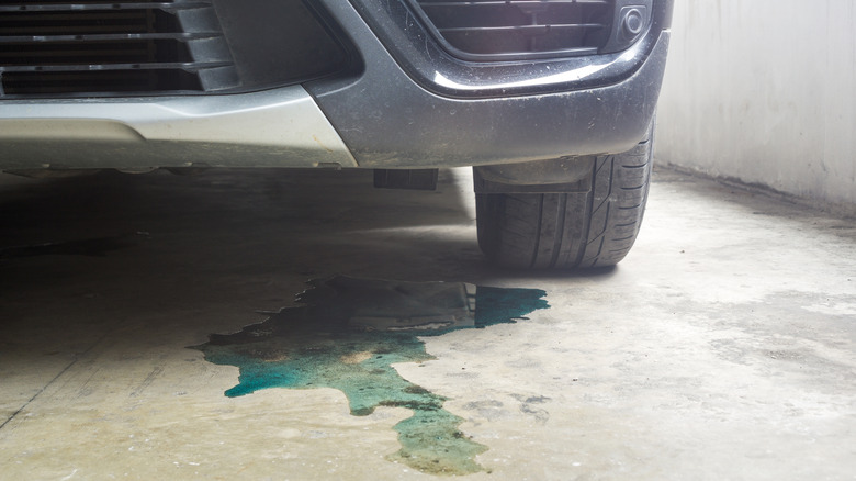 A parked car with a puddle of coolant beneath it signaling a leak in the system somewhere