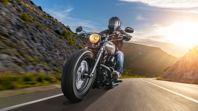 A biker driving a motorcycle during sunrise on empty road