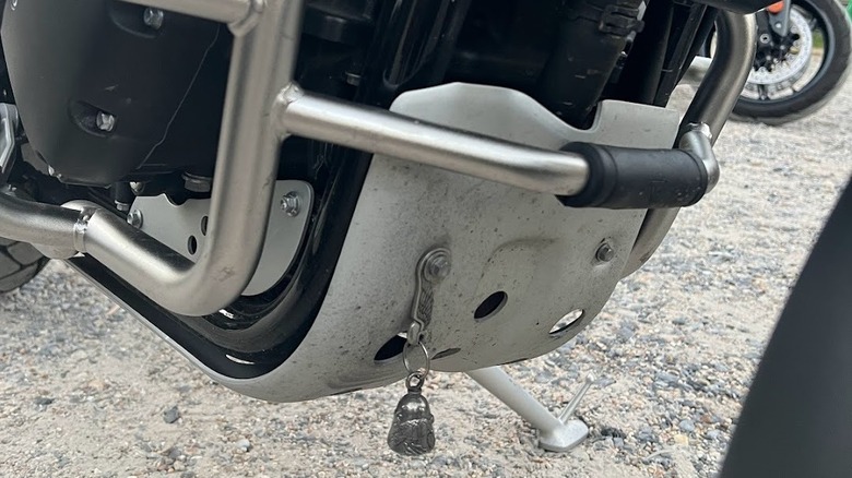 A silver Gremlin Bell hanging at the bommom of a Triumph motorcycle