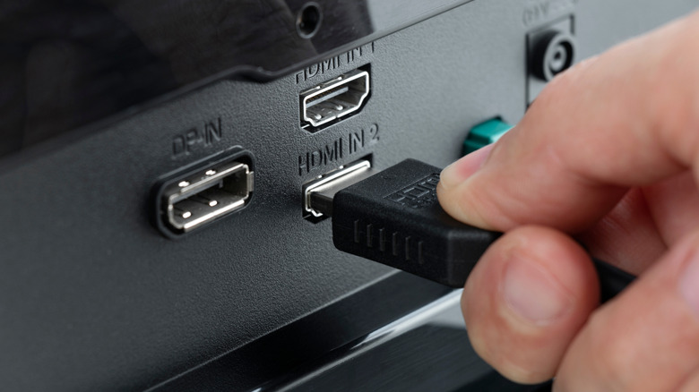 A person plugging an HDMI cable into a device's HDMI port