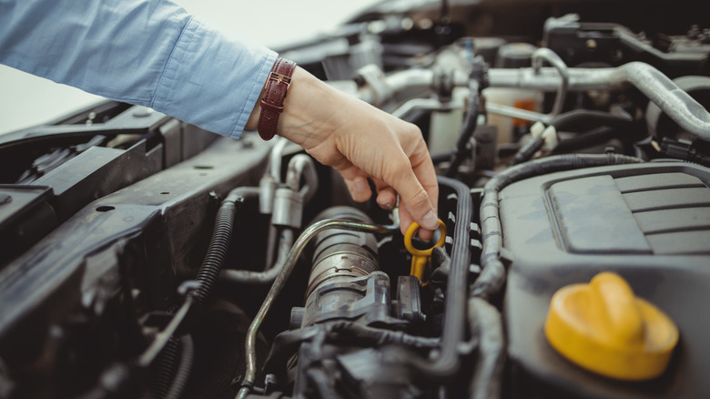 A person removing a dipstick from an engine