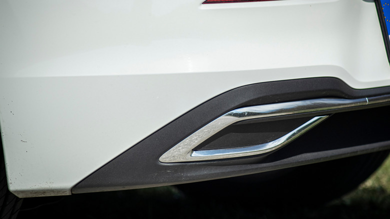 A close-up of a fake exhaust tip on a white Volkswagen Golf 8