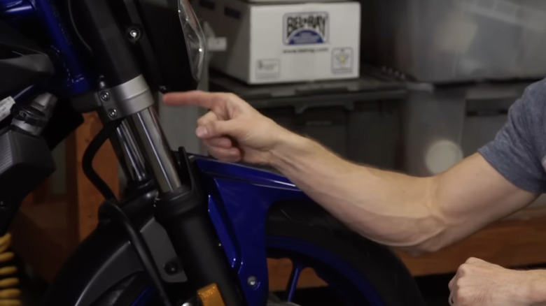 A man points to an inverted suspension on a motorcycle